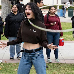 A Fullerton Collage student spins a hula hoop around her neck during a campus event.